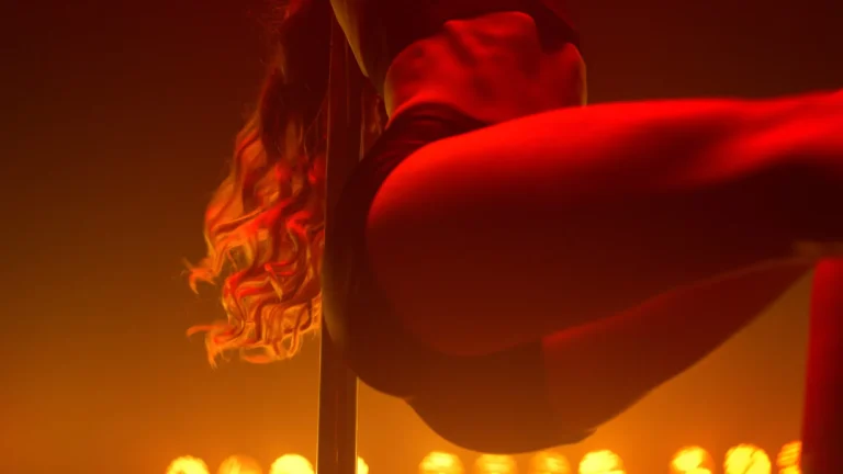 Fit woman dancing erotic moves in strip club. Closeup body performing poledance